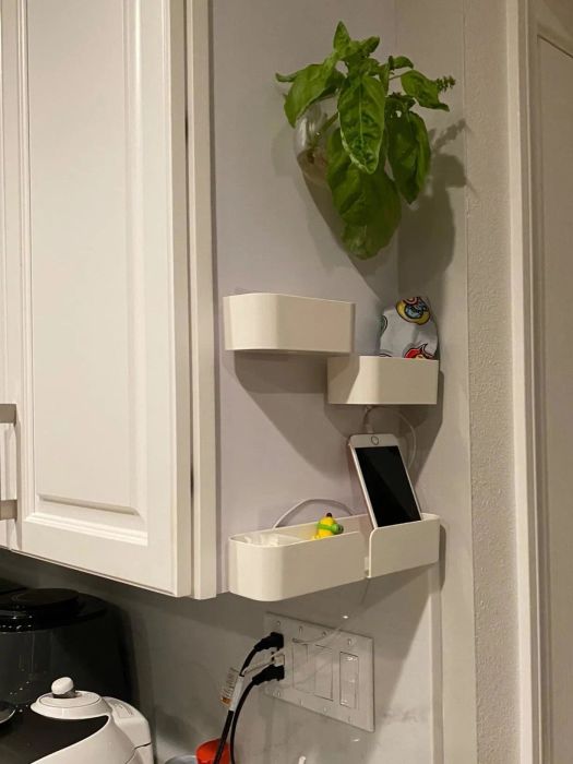A reviewer's photo of three shelves attached to the side of a white cabinet, holding a phone and a few small knick-knacks.