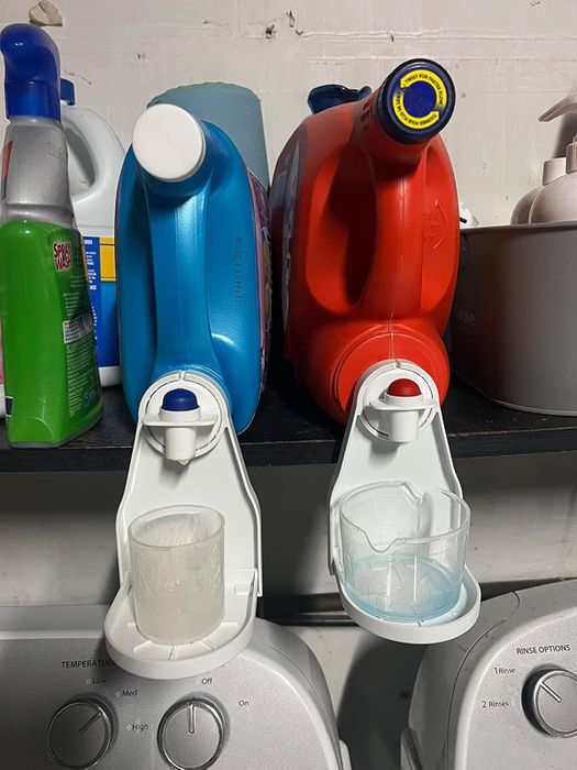 A photo from a reviewer showing two bulk detergent bottles with cup holders attached to the spouts