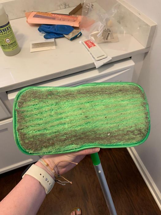 A reviewer's Swiffer with a mop pad attached, showing all the dirt it collected