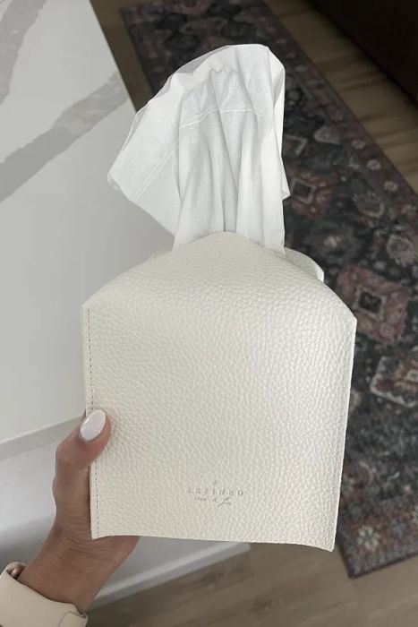 A reviewer showcasing a white faux leather tissue box cover