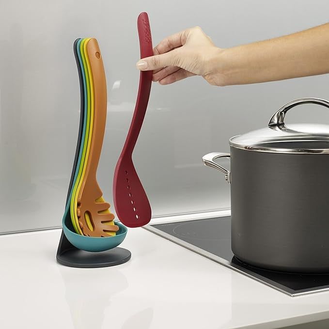 Colorful utensils neatly stacked in their holder with a hand grabbing one