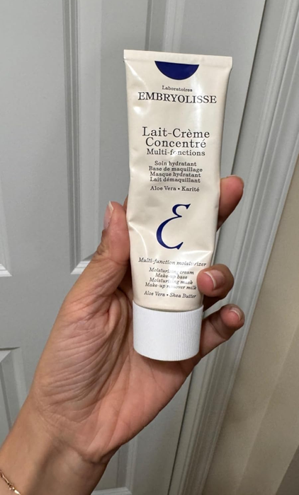 Hand holding a tube of Embryolisse Lait-Crème Concentré