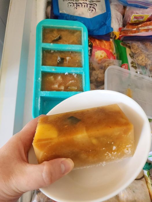 A reviewer proudly holding up a frozen block of soup made with silicone cubes.