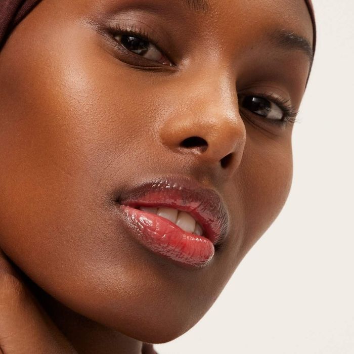 Close-up of a person with glossy lips and smooth skin, showcasing beauty products in a shopping guide