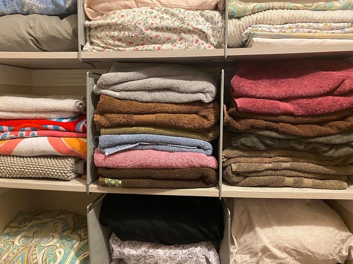 A photo showing how shelf dividers can be used to neatly separate towel stacks in a linen closet, keeping everything organized and accessible.