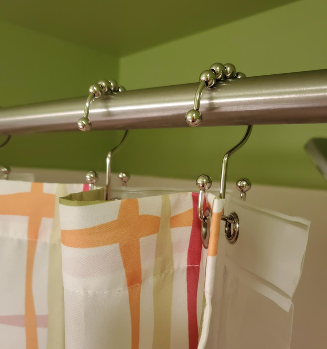 A reviewer’s shower curtain featuring dual rings, one for the curtain and one for the liner, in action