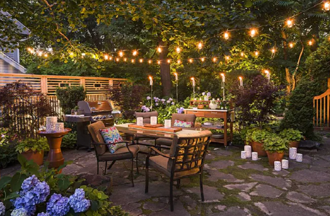 A shot of string lights draped above patio furniture in a backyard setting.