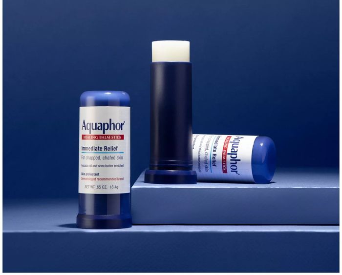 Aquaphor Healing Balm Stick with cap removed, revealing the product. The text emphasizes its handy, mess-free applicator for relieving chapped and irritated skin.