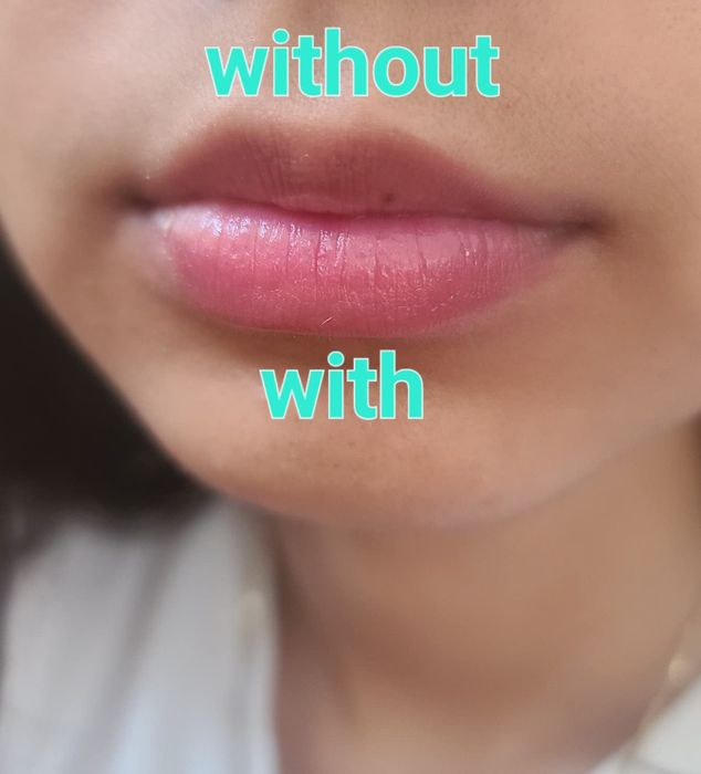 A reviewer wearing the lipstick only on their bottom lip, showing how it creates a subtle pink and shimmery finish
