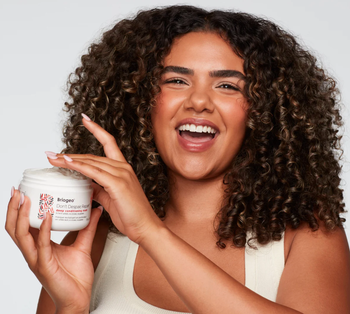 A model holding the jar of the hair mask with the lid off
