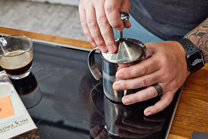 A close-up of someone using the HIC Fino Milk Frother