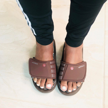 A person wearing branded slide sandals, shot from above