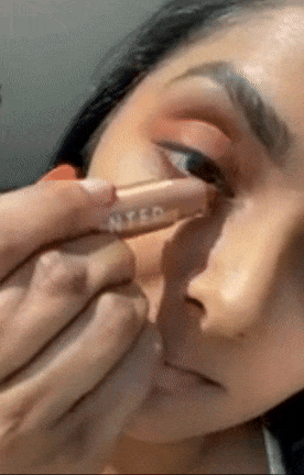 A person applying eye makeup using a precision brush for detailed application.