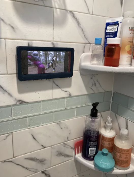 A reviewer enjoying a TV show while in the shower, thanks to their waterproof phone holder.
