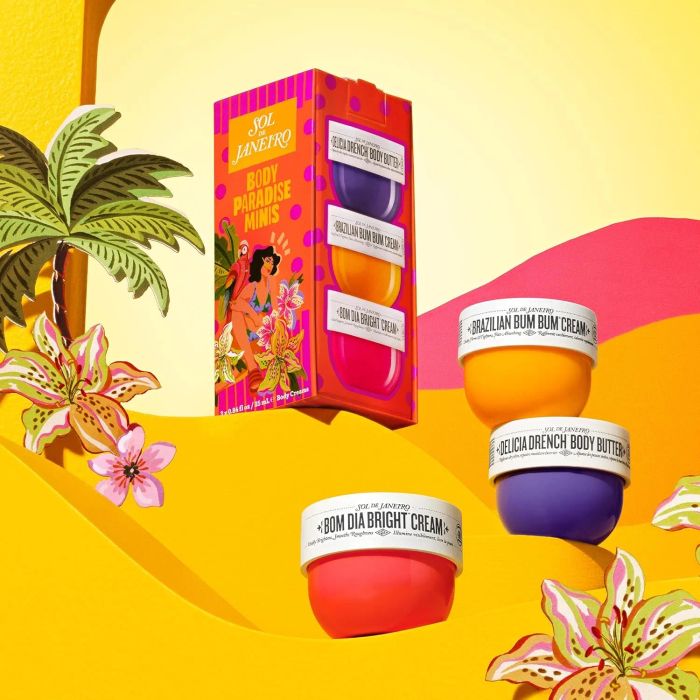 Sol de Janeiro Body Paradise Minis set beside tropical flowers, showcasing three cream varieties: Brazilian Bum Bum, Bom Dia Bright, and Beija Flor Elasti-Cream.