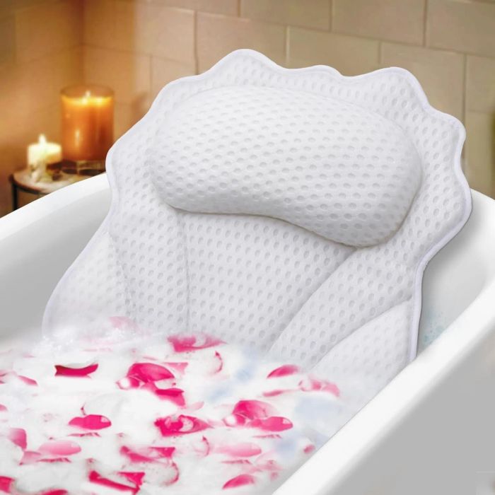 A bathtub scene featuring a plush white bath pillow with a textured surface. The water is filled with bubbles, and delicate pink rose petals float atop, creating a tranquil atmosphere.