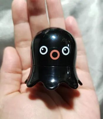 A small black octopus-shaped remover in a reviewer's hand