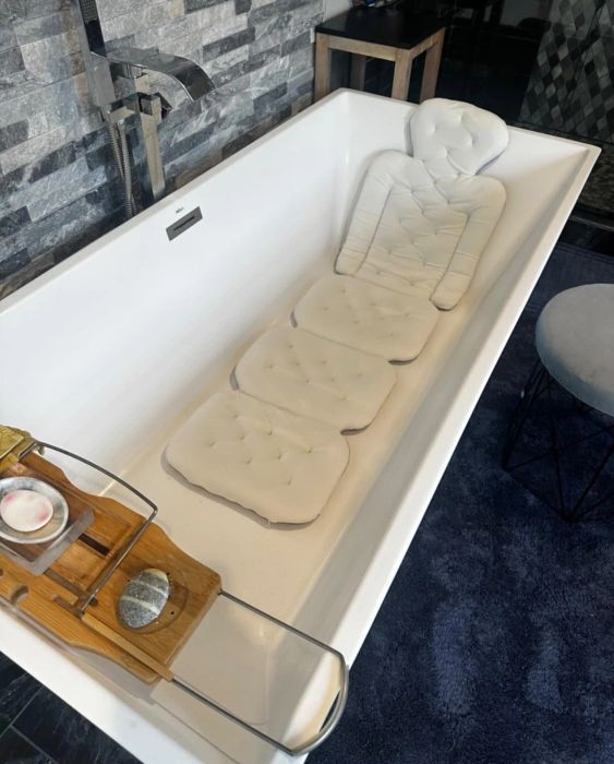 A luxurious bathtub with a padded insert, a wooden tray holding bath essentials, set in a sleek, modern bathroom design.