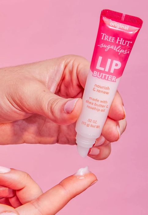 Hands applying Tree Hut Sugarlips Lip Butter, made with shea butter and rosehip oil.
