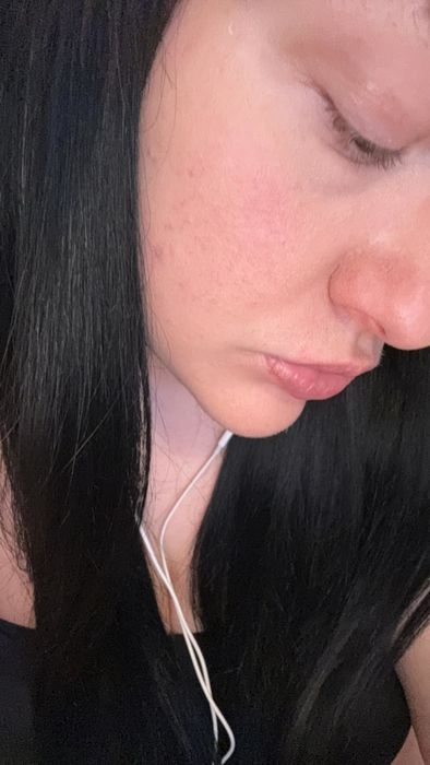 Close-up of a person with long black hair and perfectly even, redness-free skin