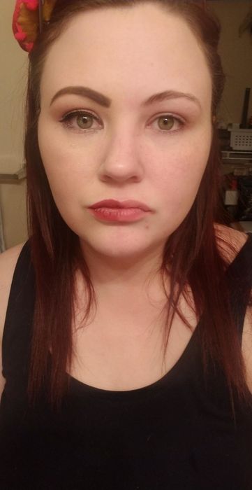 A reviewer with one half of their face fully made up and the other half bare after using the eraser.