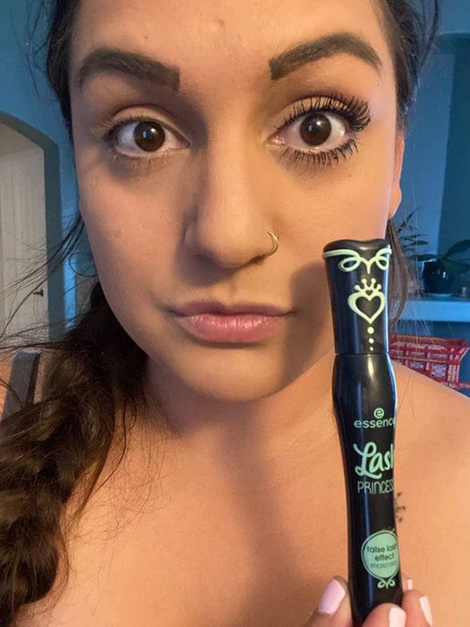 A reviewer holding the mascara tube with it applied to one eye, showing a noticeable difference.