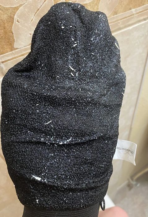 A reviewer’s hand wearing the black mitt, showing dead skin sloughed off