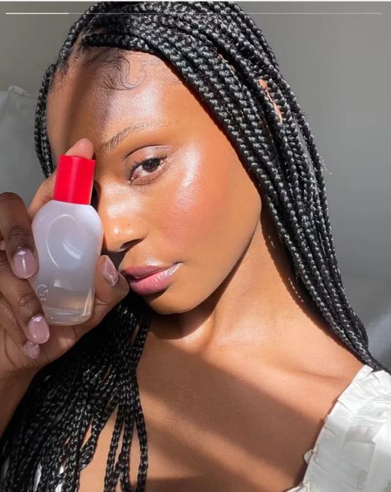 A person holding a bottle with a vibrant red cap, ready for use.