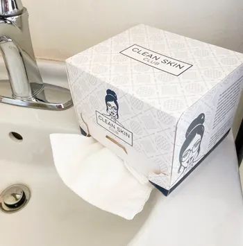 A square towel dispenser with 50 soft towels neatly stacked inside.