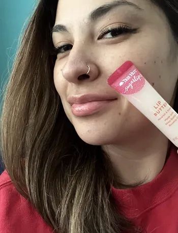 A model holding a lip butter product.