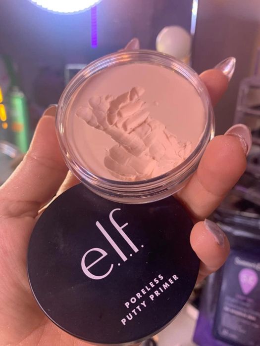 A reviewer holding a container of primer with some of the product shown to highlight its consistency