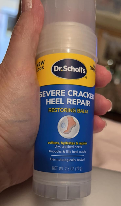 A hand holding Dr. Scholl's Severe Cracked Heel Repair balm for dry, cracked heels