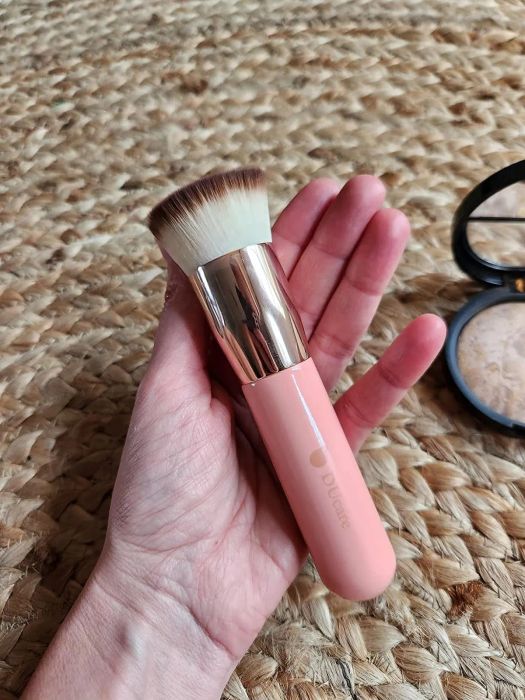 A hand gracefully holding the Doucce makeup brush.