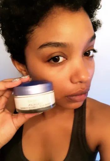 A reviewer holding the jar of L'Oréal Collagen Moisture Filler, ready to use it.