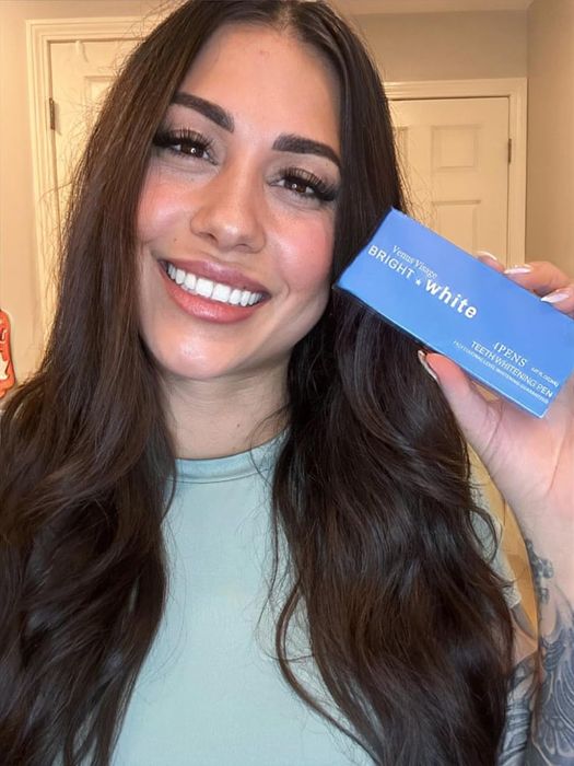 The reviewer holding a box that contains whitening pens, ready to transform your smile.