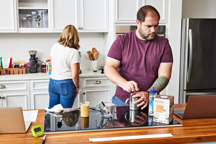 A person holding the HIC Fino Milk Frother while looking at a laptop