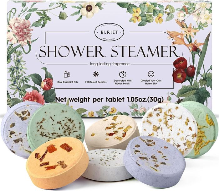 Shower steamers in a variety of scents with floral designs, placed in front of packaging labeled 'Blriet Shower Steamer, Long Lasting Fragrance.'