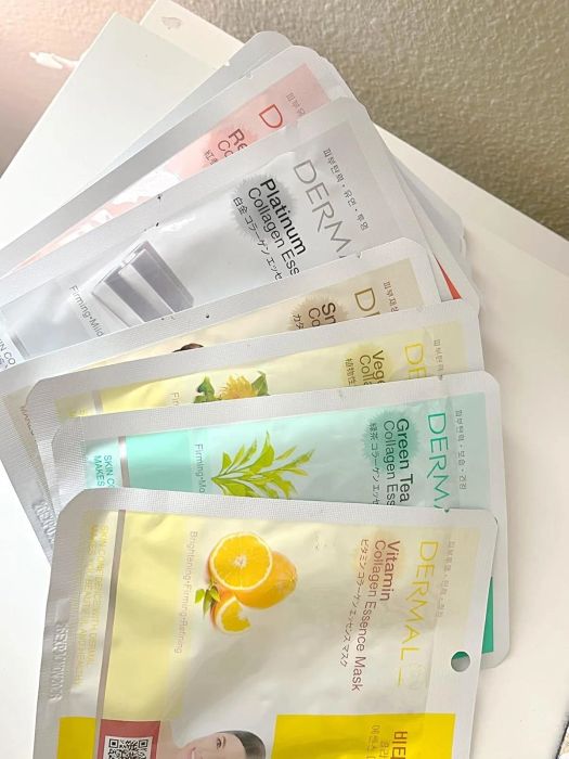 A collection of Dermal face masks featuring various ingredients such as collagen, vitamins, and green tea, arranged on a table