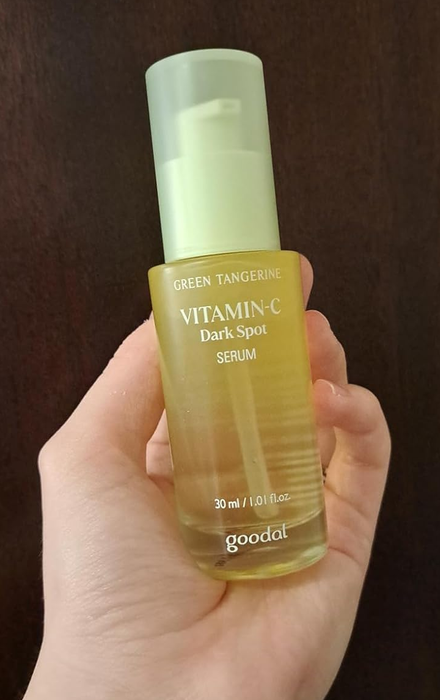 A hand holding the Goodal vitamin C serum bottle.