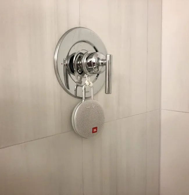 A reviewer’s JBL speaker attached to their shower faucet, playing music in the shower.