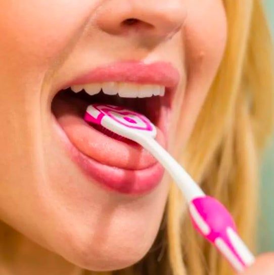 A close-up of someone brushing their tongue with a toothbrush, demonstrating correct oral hygiene practices.