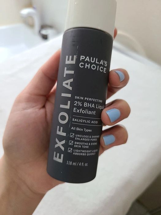 A reviewer holding the full-sized 4-ounce bottle of the exfoliant.