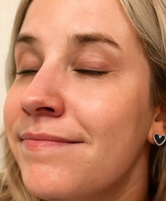 A reviewer with eyes closed, displaying smooth skin, and wearing heart-shaped earrings.
