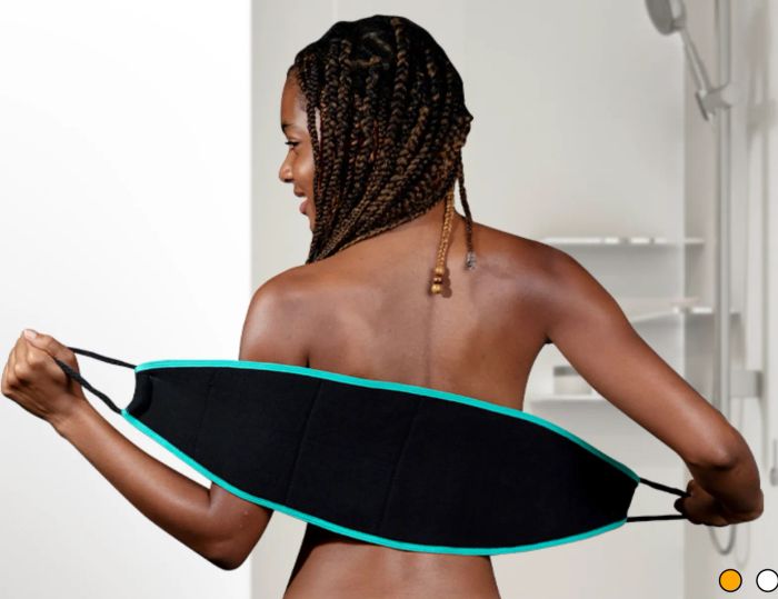 A model demonstrating the use of a back scrubber with a black handle strap for exfoliation.