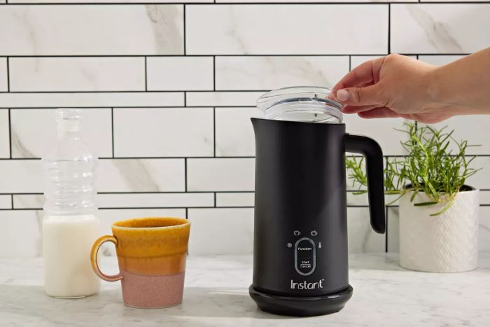 A hand lifting the lid of the Instant Pot Instant Milk Frother