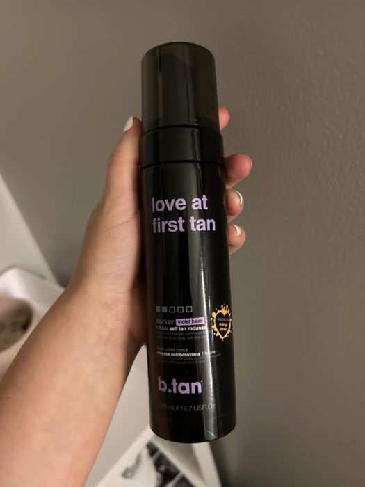 A reviewer holding up a spray can of the self-tanner.