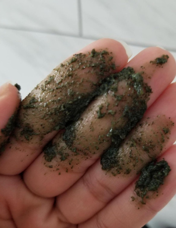 Close-up of a hand applying the green exfoliating formula.