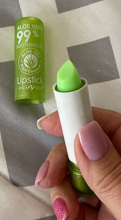 A reviewer holding a tube of green lipstick