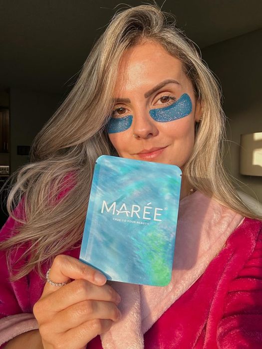 Reviewer wearing the blue, glittery under-eye patches while holding the packaging