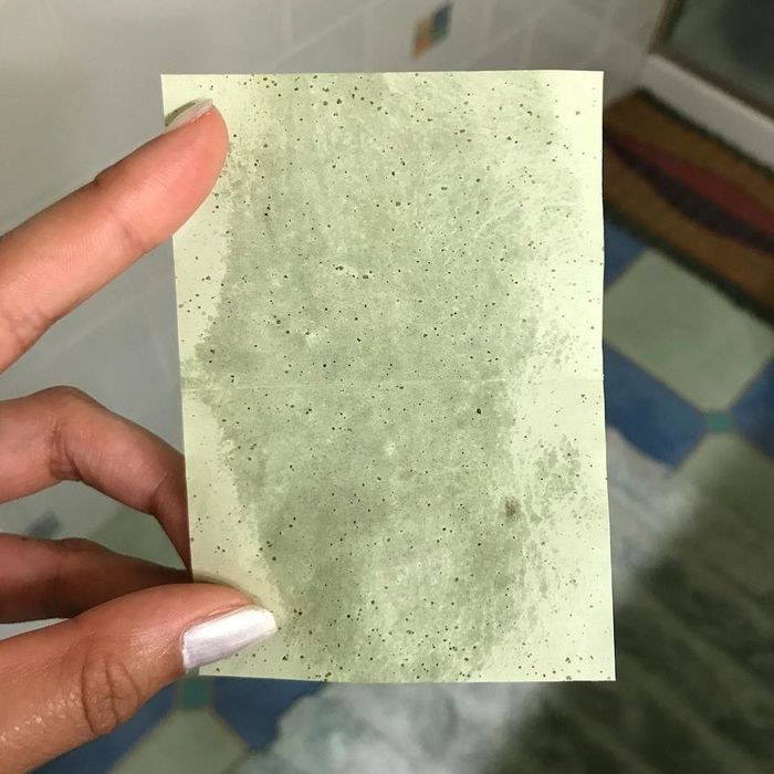 A used green oil-blotting sheet from a reviewer, showing it soaked in oil.